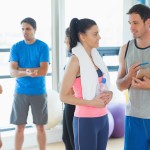 Fit couple with friends standing in background in bright exercise room